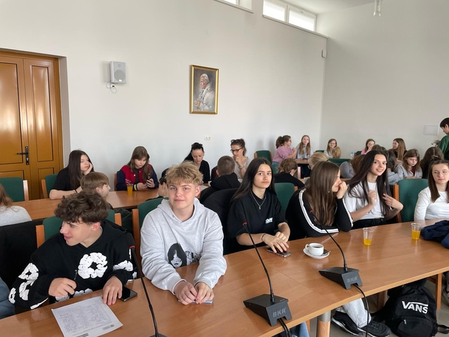 3-_Uśmiechnięci_wolontariusze_wpatrzeni_w_obiektyw_na_drugim_planie_nauczycielki_podpisujące_listy_obecności-_Easy-Resize-com
