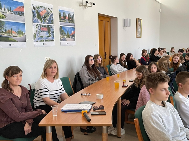 7-_Kierownik_Ośrodka_Pomocy_Społecznej_i_koordynator_zbórki_siedzące_z_wolontariuszami_przy_zaokrąglonym_stole-_Easy-Resize-com