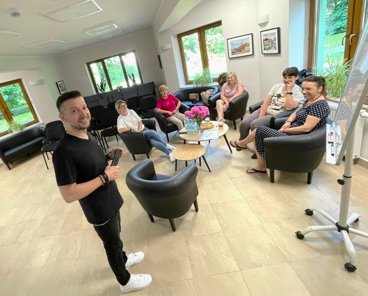 Kadr z góry od strony tablicy przedstawia wszystkich uczestników szkolenia przodem