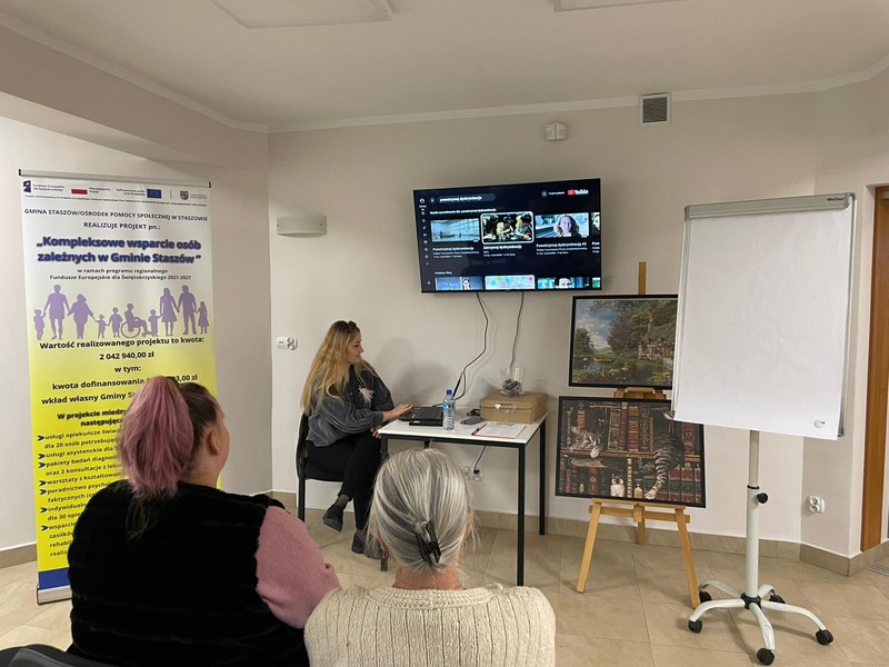 Dwie kobiety siedzą tyłem do obiektywu przed nimi siedzi pani patrząca w ekran laptopa