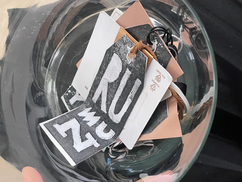 Szklany pojemnik w środku metki z zapisanymi róznymi narodowościami na pierwszym tle metka z napisem rumun