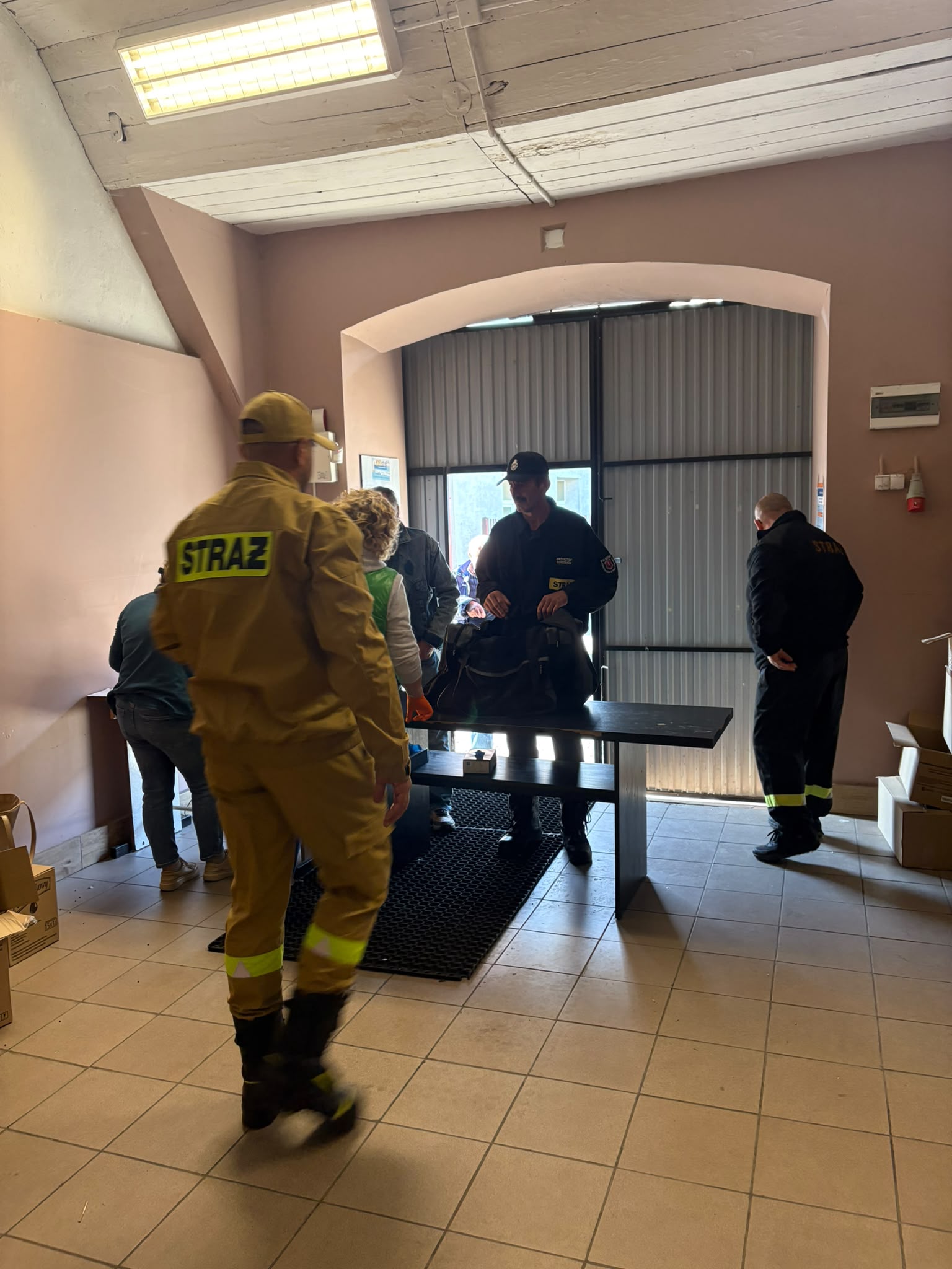 3. Na zdjęciu strażacy stoją tyłem i&nbsp;wydają żywność.