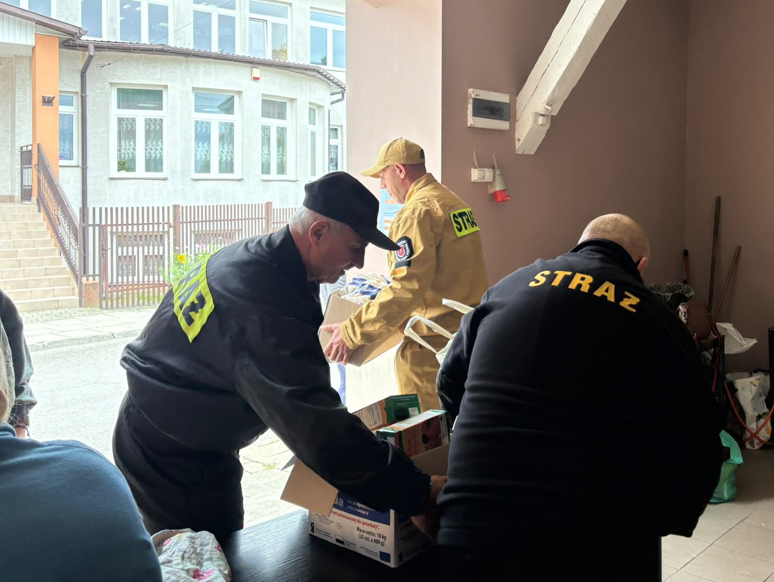 6. Na zdjęciu strażacy noszą paczki z&nbsp;żywnością.